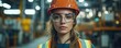 © Georgii - Confident female engineer wearing safety vest and hard hat in industrial setting