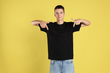 Poster - Teenage boy wearing black t-shirt on yellow background