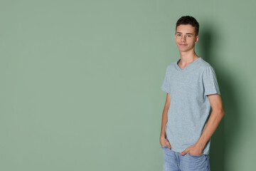 Poster - Teenage boy wearing light grey t-shirt on green background, space for text