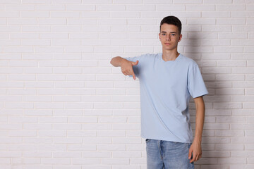 Canvas Print - Teenage boy wearing light blue t-shirt near white brick wall, space for text