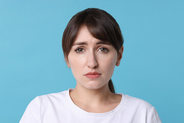 Poster - Portrait of frustrated woman on light blue background