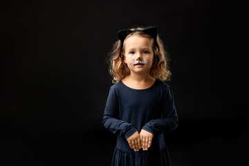 Wall Mural - Funny girl dressed like cat for Halloween celebration on black background