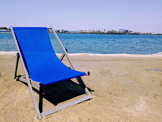 Blue beach chair on the sandy beach with sea and blue sky on background