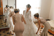 © Vasil - A bride is getting ready for her wedding with her bridesmaids. The bridesmaids are helping her get dressed and are standing around her