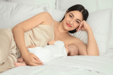 Wall Mural - Young woman breastfeeding her baby in bedroom