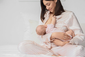 Poster - Happy mother breastfeeding her little cute baby in bedroom