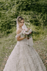 Wall Mural - A woman in a white dress is holding a bouquet of flowers. She is standing in a field of grass