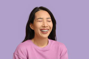 Sticker - Young Asian woman laughing on lilac background