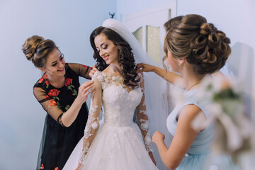 Wall Mural - Three women are getting ready for a wedding. One of them is putting a veil on the bride