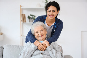 Canvas Print - Young African-American female medical worker with elderly woman in nursing home