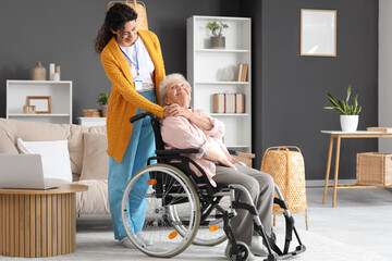 Wall Mural - Young African-American female medical worker with elderly woman on wheelchair in nursing home