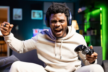 Happy gamer feeling excited after finally defeating all foes and winning game, celebrating, punching air. Joyous man congratulating himself after finishing videogame on gaming console