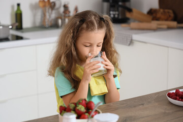 Wall Mural - Cute little girl with glass drinking yogurt in kitchen