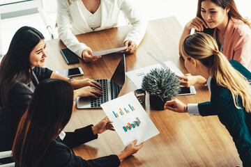 Businesswoman in group meeting discussion with other businesswomen colleagues in modern workplace office with laptop computer and documents on table. People corporate business work team concept. uds