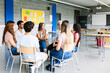© Xavier Lorenzo - Young group of teenage students discussing in classroom sitting in circle with female teacher, giving an opinion on a debate topic. Education concept