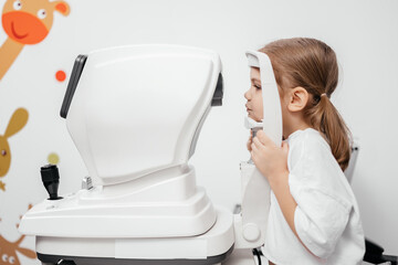 In a modern ophthalmology clinic, an ophthalmologist checks a little girl's vision using a binocular slit lamp. Advertisement for pediatric ophthalmology