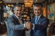 © engkiang - Two senior businessmen in formal attire shaking hands, symbolizing business partnership or agreement, in a professional office environment..