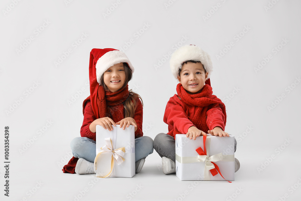 Cute little children with Christmas gifts on light background