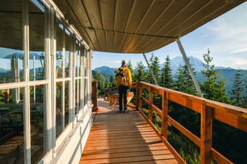 Man with a dog is on top of Suntop Peak on Suntop Fire Lookout at sunset, Mount Rainier and the White River Valley in Washington State USA