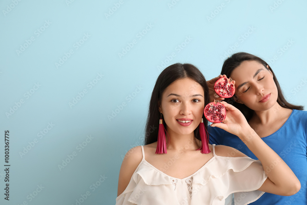 Beautiful young women with fresh pomegranate on blue background