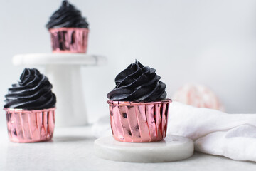 Sticker - Black frosting on Pink cupcakes with a white background, cupcakes in pink foil liners with black buttercream