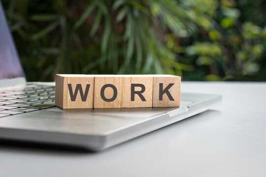 Work, word written on square wood block, on top of computer laptop.