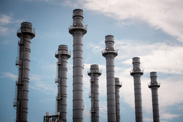 Engineers wearing safety gear, including hard hats examining survey a large blueprint tablet standing industrial facility gas or oil refinery engaged in a job requires high safety standards concept