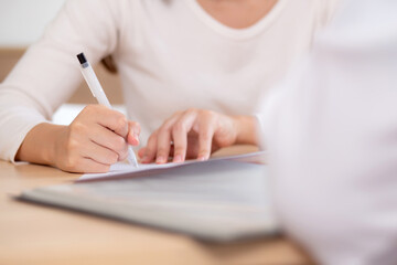 Closeup hand writing on paper for signature about insurance or agreement medical in modern medical office, contract or finance about medical, hand woman signing with doctor for treatment in hospital.