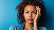 © Andres Mejia - Young woman with curly hair is touching her face with a painful expression