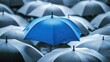 © savittree - Blue umbrella shining brightly among gray umbrellas, symbolizing the business concept of standing out and offering protection.