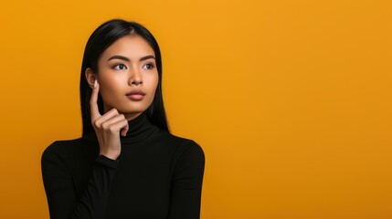 Stunning Asian woman presenting on yellow backdrop exuding beauty, confidence, and elegance in a fashionable and happy portrait.