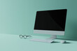 © Henry Saint John - Minimalist office desk setup with computer monitor, keyboard, and eyeglasses on pastel background.