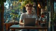 © Johannes - Young man working on laptop, boy freelancer or student with computer in cafe at table looking in camera. Model by AI generative