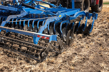 Rear view of a large tractor with a plow standing in a field. Start tillage after harvest.