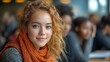 © Budi - A young woman with curly hair and an orange scarf smiles in a classroom setting.
