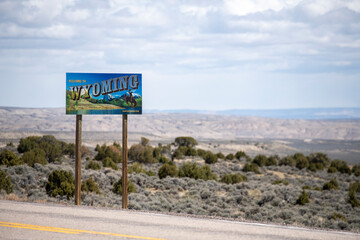 Sticker - Welcome to Wyoming sign along rural highway overlooking valley