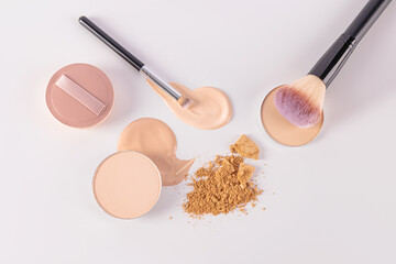 Delicate cosmetic background in light colors with two makeup brushes, a round sponge on a sample of foundation liquid powder. top view. Flat lay.