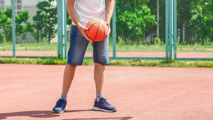 Active young male playing street basketball, dribbling ball, training on court