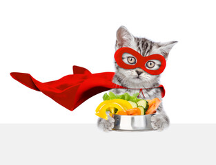 Aufkleber - Funny kitten wearing superhero costume holds bowl of vegetables above blank white banner. Isolated on white background