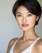 © thiquynh - an Asian woman with short hair, wearing a white tank top, against a simple background with light and shadow