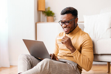 Aufkleber - Happy African American Student Guy Using Laptop Studying And Having Coffee Sitting On Floor At Home On Weekend. Selective Focus