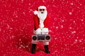 Wall Mural - Full length photo of pensioner old man grey beard hold boombox open mouth wear santa x-mas costume gloves coat belt sunglass headwear black boots isolated red color background