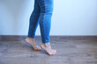 © Vin.rusanov - Female legs in jeans on a wooden floor, close-up.