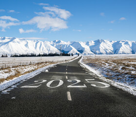 Wall Mural - New Year 2025. Text 2025 written on Lake Ohau road. Snow-capped mountain ranges in the distance. Lake Ohau. New Zealand.