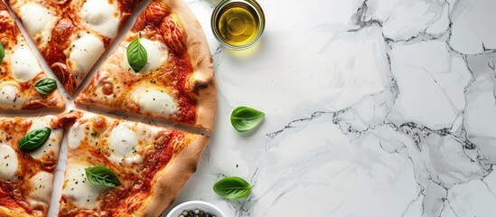 Homemade sliced cheesy classic Italian pizza with toppings and olive oil on a white marble background with copyspace viewed from above