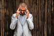 © djoronimo - Portrait of young businessman who is having headache. Wooden background.