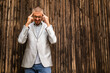 © djoronimo - Portrait of young businessman who is having headache. Wooden background.
