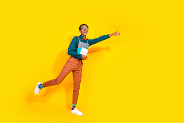 Wall Mural - Full body photo of funny young man superhero fist hold copybooks dressed stylish suit clothes isolated on yellow color background