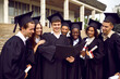 © Studio Romantic - Group of happy multiracial university graduates look at their diploma after graduation ceremony. Boy is holding album while standing surrounded by his classmates in courtyard of university.