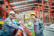 © sirichai - factory workers in uniform together work inspecting operation manufacturing Metal Roofing Sheet Machine in the factory metal sheet, Metalwork roof manufacturing and quality control process.